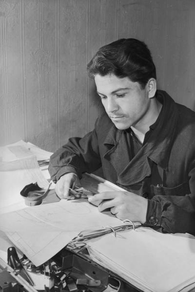 Инженер с чертежами, 1955 - 1965. Молодой юноша работает с чертежами, используя штангенциркуль.